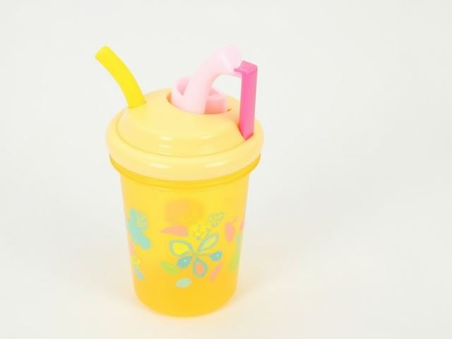 A colorful straw cup for children with a cute design, featuring fun patterns and an easy-to-hold handle.